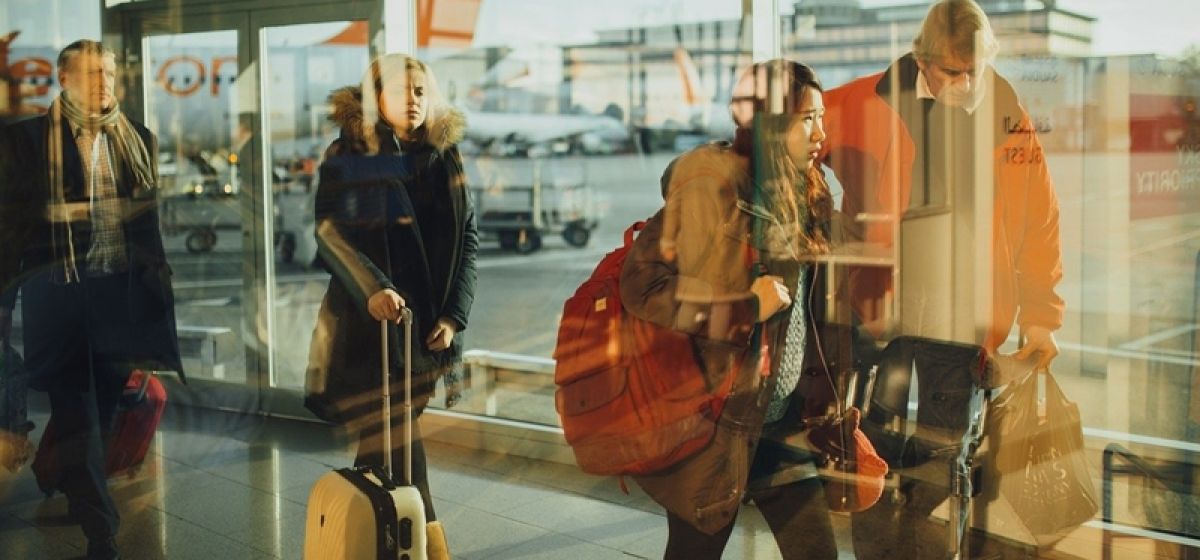 Personas guardando cola en un aeropuerto con maletas
